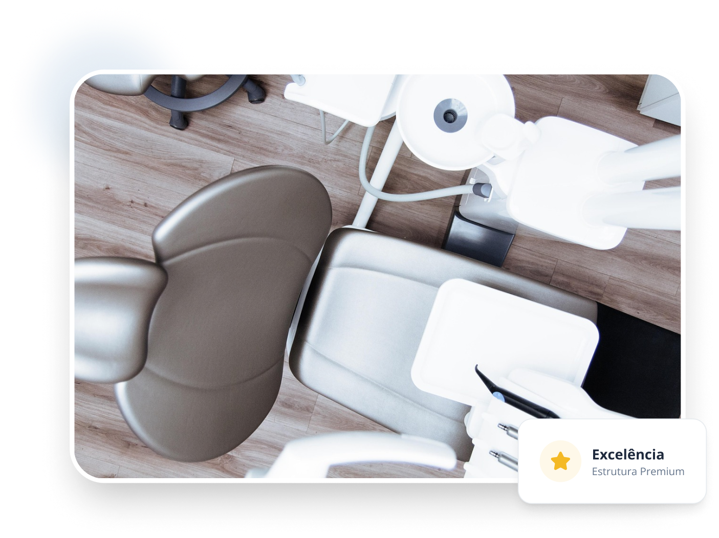 Vista aérea de uma cadeira odontológica moderna em tons de cinza e prata, cercada por equipamentos médicos brancos, cuspideira e bandejas de instrumentos sobre um piso que imita madeira clara